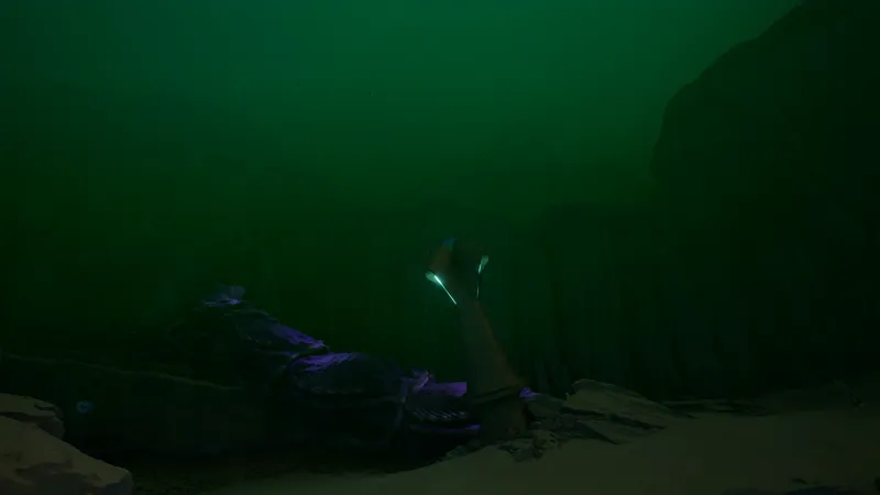Subnautica 2 Root Canyon biome — deep green water with stone column and bioluminescent tip, purple creature on canyon floor
